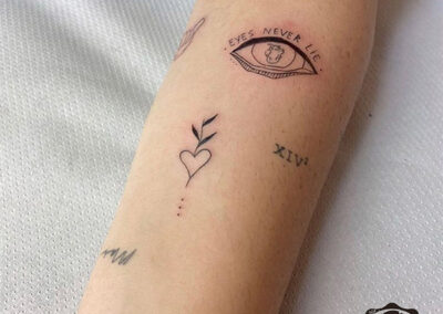 tatuajes finos ojo y corazón en antebrazo