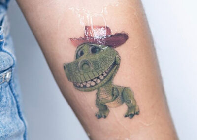 Micro realismo tattoo de un un dinosaurio en dibujo animado