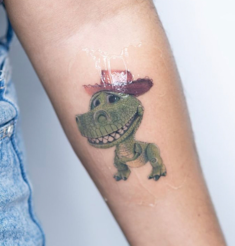 Micro realismo tattoo de un un dinosaurio en dibujo animado