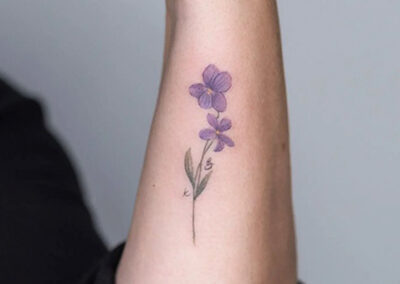 tatuajes flores moradas en brazo de mujer