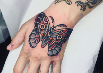 Tatuaje en la mano de una mariposa old school