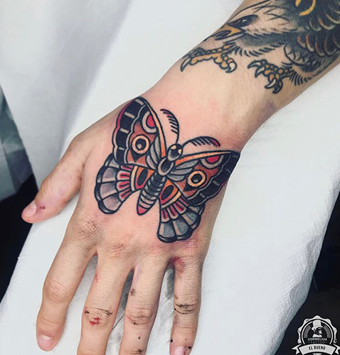 Tatuaje en la mano de una mariposa old school