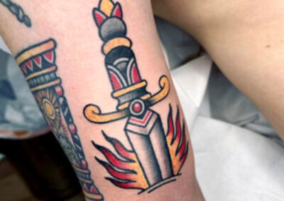 Tattoo estilo old school de una espada clavada con llamas | Tattoo Madrid