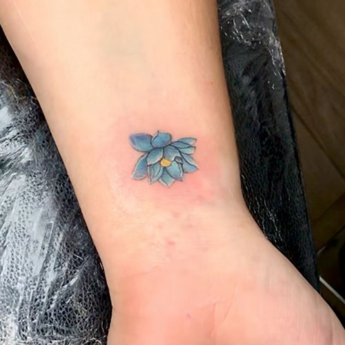 tatuaje pequeño de una flor azul en el brazo | tatuajes pequeños para mujer |  tatuarse en Madrid | Cornelius Tattoo